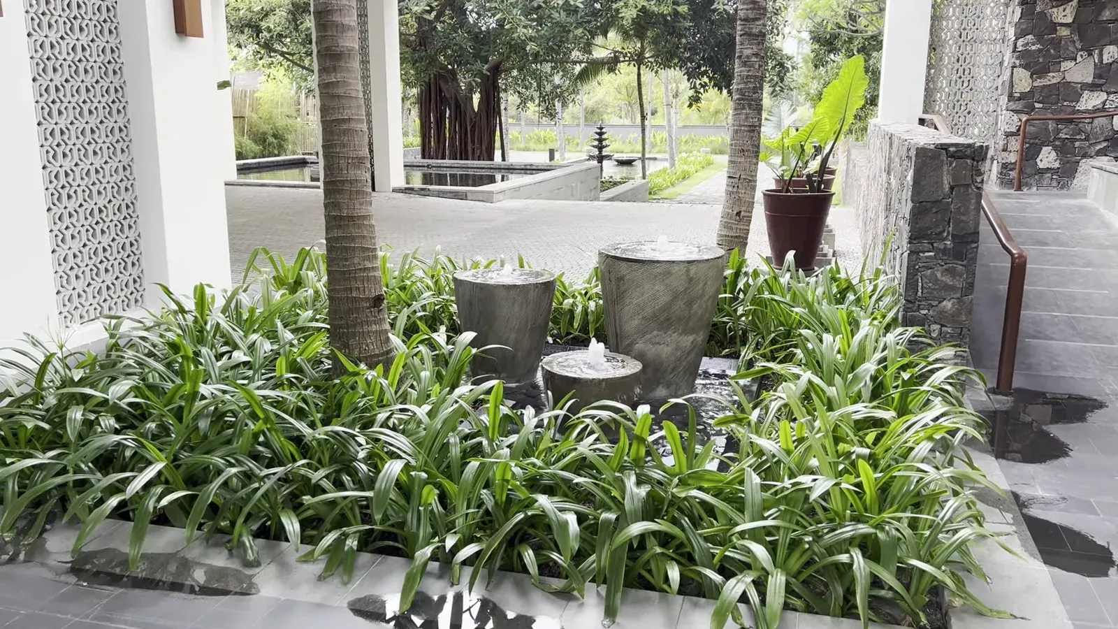 The planted walkway with stone fountains leading to the lobby at The Sira Lombok