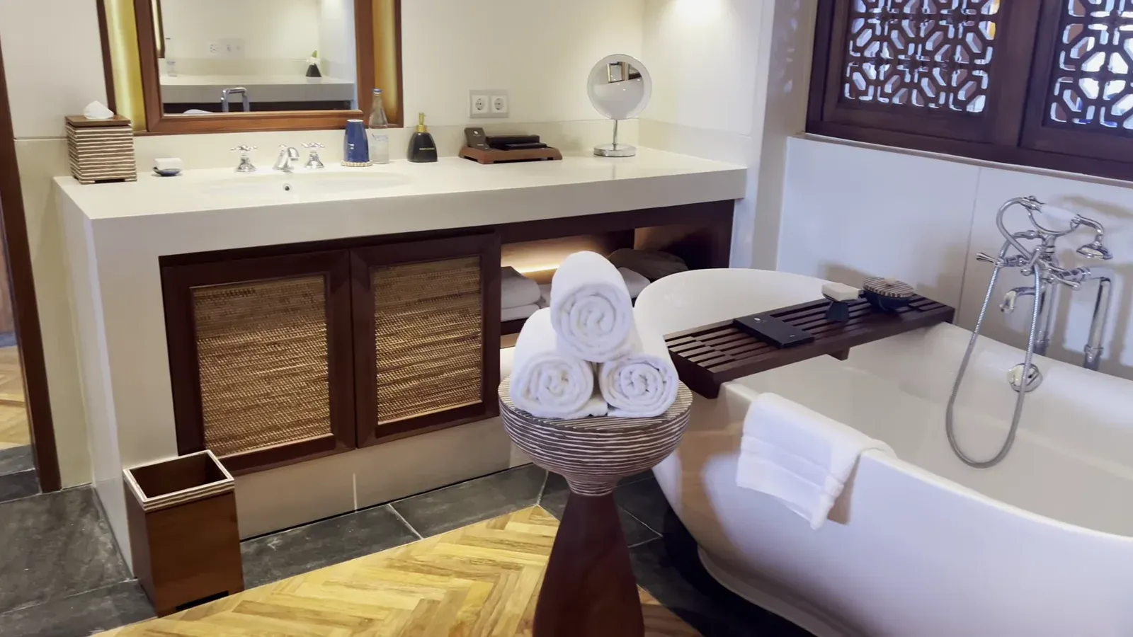 The double vanity in the suite bathroom, with the tub and rolled towels behind